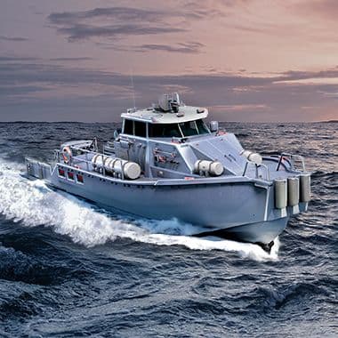 Modern military patrol boat with mounted weapons cruising through ocean waves at dusk